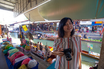 Beautiful tourost woman travel in floating market take photo at Amphawa is a very popular floating...