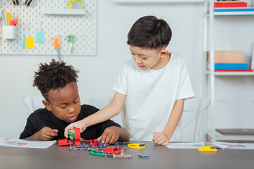 Two boys practicing their learning skills with science toys. With electronic electrical connection simulation robot, brain development and learning experiment circuit board. to become future inventors