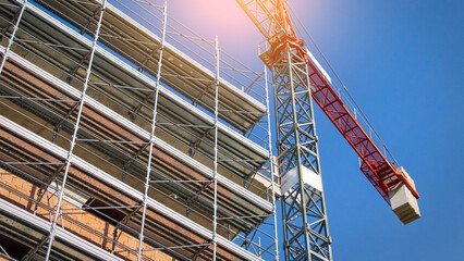 Building under construction with scaffoldings and crane nearby, building site with framework and...