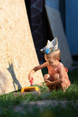 Little blond boy plays builder.Kid in T-shirt, shorts and garrison cap holds a construction...