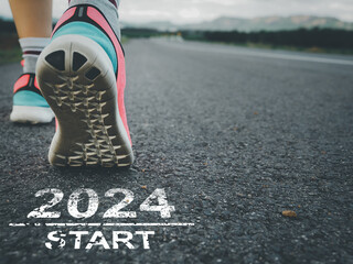 Start 2024. Female sprinter athlete preparing to run on the road with text on the road.
