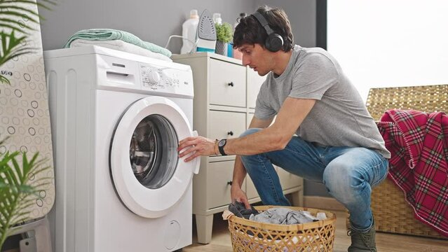 Young hispanic man washing clothes listening to music at laundry room