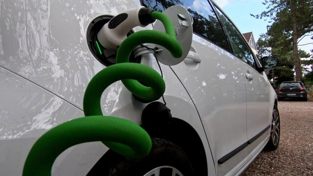 Power cable pump plug in charging power to electric vehicle EV car with modern technology , car fueling station connected power cable alternative sustainable eco energy