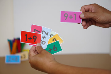 Closeup teacher hand hold paper cards with numbers addition, plus for teaching Math subject. Concept, Education, Teaching aid, materials for kids. Education, Practice calculate         