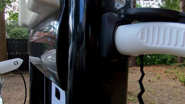Power cable pump plug in charging power to electric vehicle EV car with modern technology , car fueling station connected power cable alternative sustainable eco energy