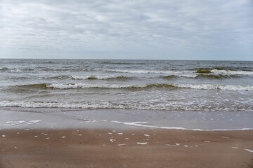 Landscape of sea waves against the beach under a cloudy sky
