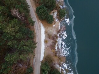Aerial shot of a beach surrounded by the sea and greenery on a gloomy day
