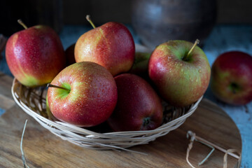 Apples in a straw basket on a wooden table