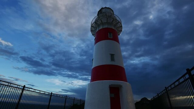 time lapse of a white and red lighthouse against a dramatic cloudy sunset sky. Wide angle