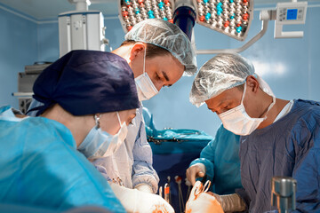 Portrait of surgeons leaned over patient during complex surgical operation in a sterile operating room. Doctors are focused and extremely attentive. Precision medicine, saving patient's life.