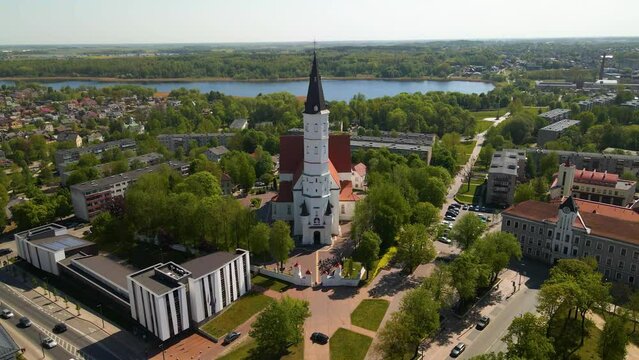 Drone footage above the city church Siauliai on a sunny day by the river Siauliai, Lithuania