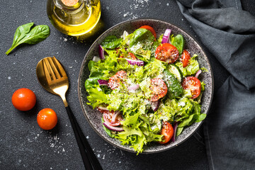 Green vegetable salad with fresh leaves at black background. Top view.