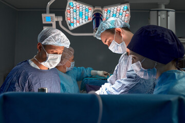 Portrait of surgeons leaned over patient during complex surgical operation in a sterile operating room. Doctors are focused and extremely attentive. Precision medicine, saving patient's life.
