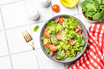 Green vegetable salad with fresh leaves. Healthy food, diet menu. Top view on white tile background.