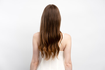 Back view of attractive brunette woman with healthy long hair posing for picture