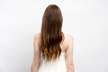 Fototapeta premium Back view of attractive brunette woman with healthy long hair posing for picture