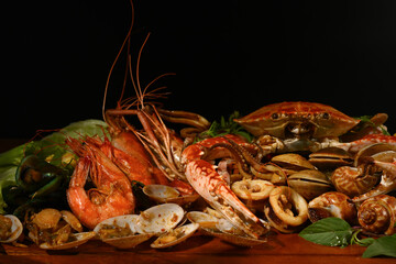 Mixed sea food on the wooden plate with black background.