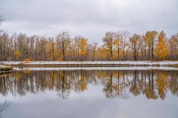 the lake has yellow and brown trees on both sides of it