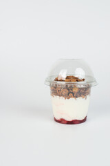 Yogurt with granola flakes and fruits in a plastic cup to go