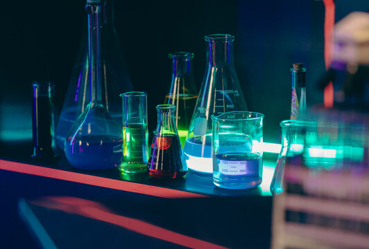 vue sur des contenants en verre rempli de liquides color&eacute;s &eacute;clair&eacute;s par derri&egrave;re sur une tablette