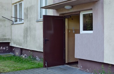 An old building of a block of flats from the 70s with an open entrance door to the stairwell