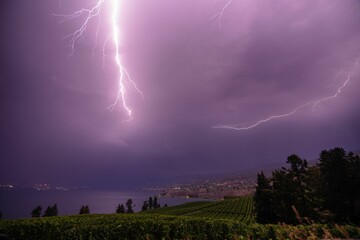 Naklejka na ściany i meble Dramatic image of a stormy lightning sky over Okanagan Lake and the Naramata Bench vineyards