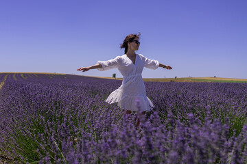 Fototapeta na wymiar Woman spinning and walking through lavender field