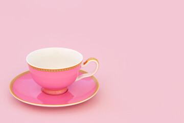 Pink and gold bone china tea cup. Elegant luxury drinking set on pastel pink background with copy space. Minimal zen composition.