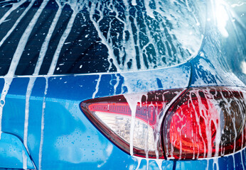 Blue car wash with white soap foam and professional auto care service. Car cleaning service...