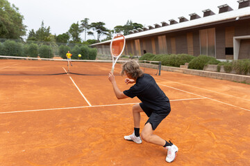 Two sportive boys playing friendly tennis match on the court
