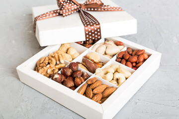 Various varieties of nuts lying in paper box on table background. Top view. Healthy food. Close up, copy space, top view, flat lay. Walnut, pistachios, almonds, hazelnuts and cashews