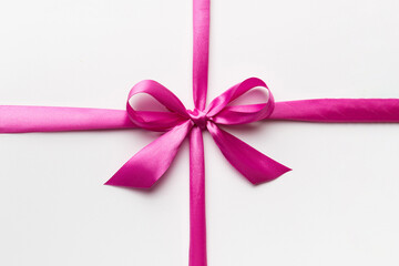 Top view of purple ribbon rolled and pink bow isolated on colored background. Flat lay with copy space