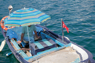 Turkey - Izmir - March 30, 2014 Photos from Old Foça, person waiting on a fishing boat, Turkey flag and sea top view

