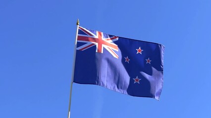 The New Zealand flag waving in the wind in the blue sky - Powered by Adobe