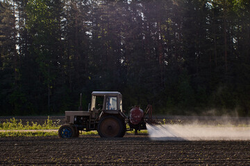 Crop sprayer with farm tractor to apply pesticides in an agricultural field.