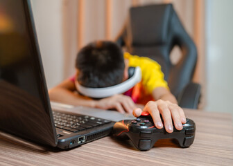 Asian boy dizzy while playing game on computer with game controller vision and vision problems in...