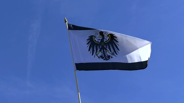 The Prussian flag waving in the wind in the blue sky