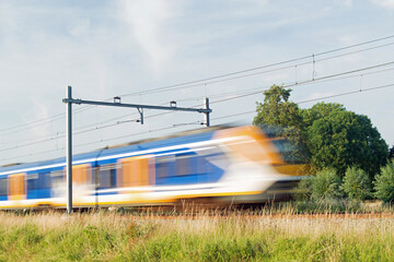 Sprinter train rushes by at high speed, blurred by motion in Arnhem in the Netherlands