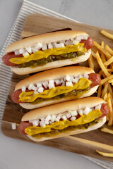 Homemade Deep Fried Hot Dogs with Mustard, Onion and Pickle Relish on a wooden board, top view.