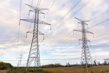 Tall steel towers supporting high voltage lines in the countryside on a cloudy autumn day