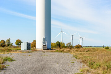 Fototapeta premium Door at the base of a tower supporting a wind turbine in a wind farm in the countryside on a sunny autumn day. Other wind turbines are visible in background.