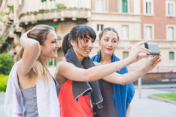 three young sportive women using smartphone taking selfie