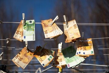 Clothesline with 100 and 50 euro banknotes suspended from it.