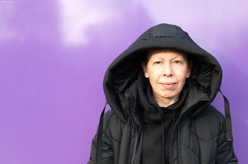 Fototapeta na wymiar Portrait of a Caucasian middle-aged woman in a black coat on a purple background