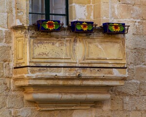 Window with several colorful flower pots sitting on its ledge.