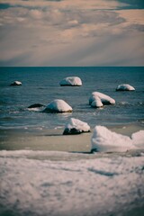 Vertical shot of the frozen seashore under a cloudy sky