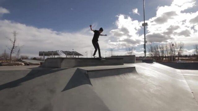 Skateboarder drifting at skatepark on a sunny day
