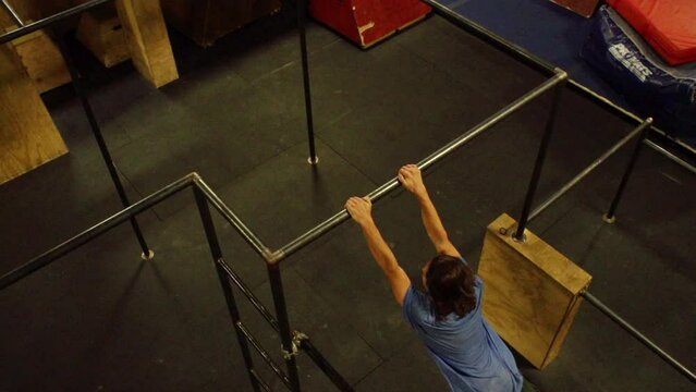 Young sportsman performing stunts and flips on parallel bars in a gym