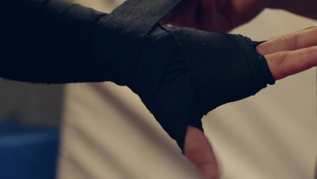 Closeup of an MMA fighter wrapping his hand with the hand bandage