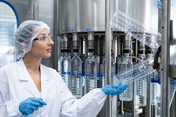 Caucasian women scientist with lab cote inspect quality of drinking water inside of the production...